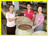 the three sisters inspect a vat of soy sauce brewed the traditional way